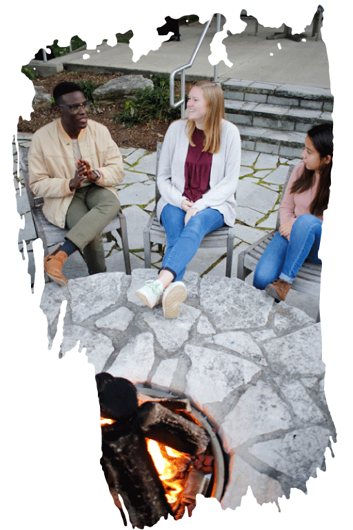 Students sitting around a small fire pit while they chat