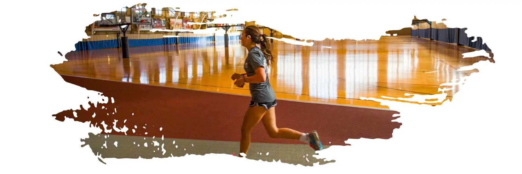 A female student running inside a gymnasium