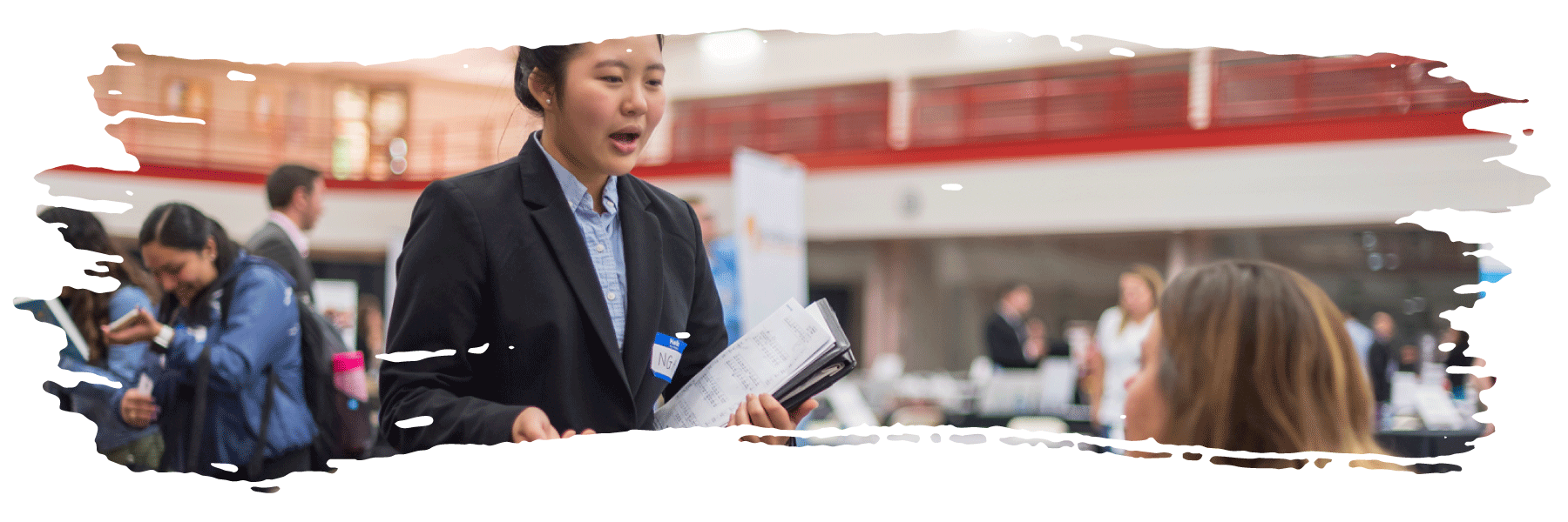 A student dressed professionally talking to an employer at their campus job fair