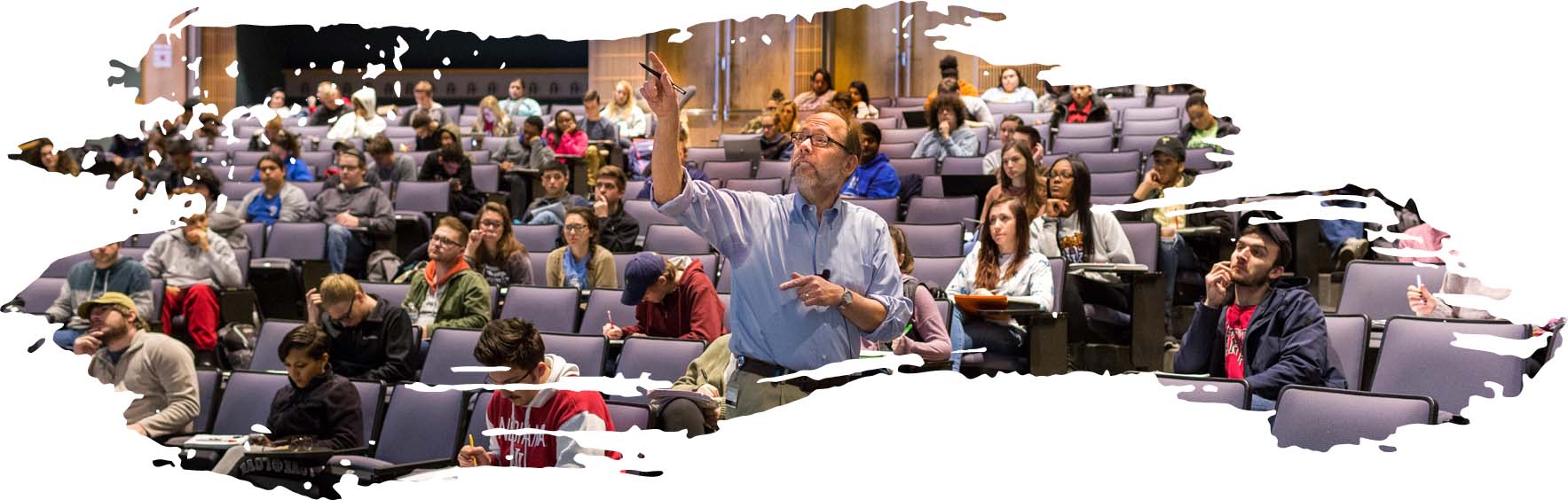 A professor speaking in front of an auditorium filled with students