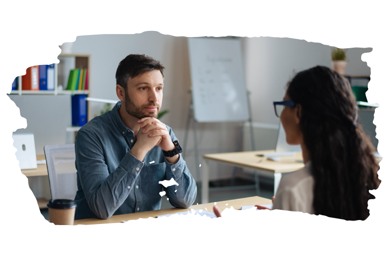 A man sitting at a desk across from a young woman and listening attentively