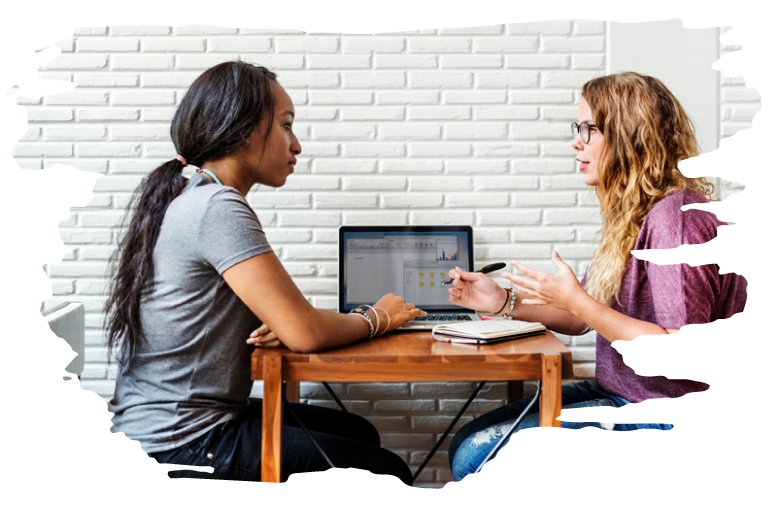 Two women sitting opposite each other at a table with a laptop