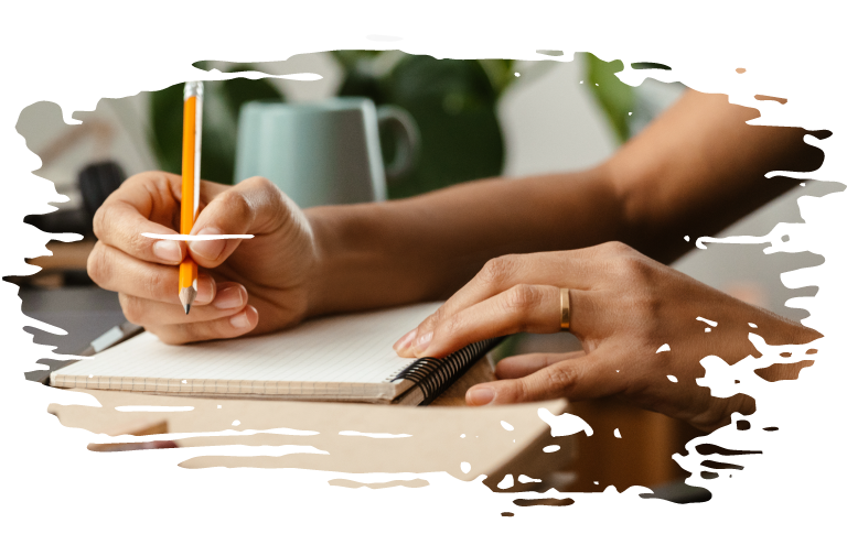 cropped photo of person holding a pencil poised over a notebook