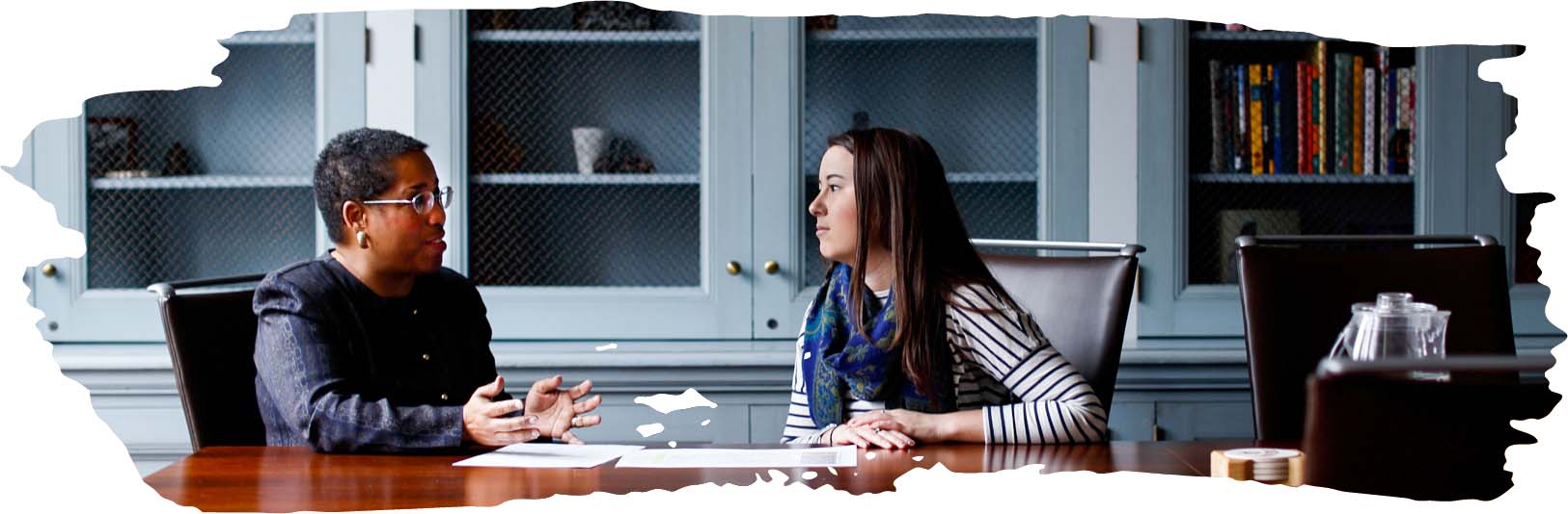 A female student talking to a female advisor at a table in the library