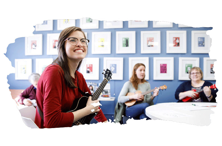 A female student smiling while holding a ukulele